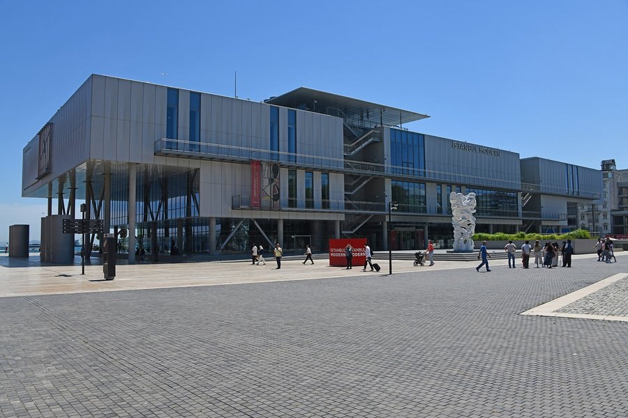 Karaköy'de deniz kıyısında, ince metal cepheli, sütunlar üzerinde yükselen İstanbul Modern müze binası