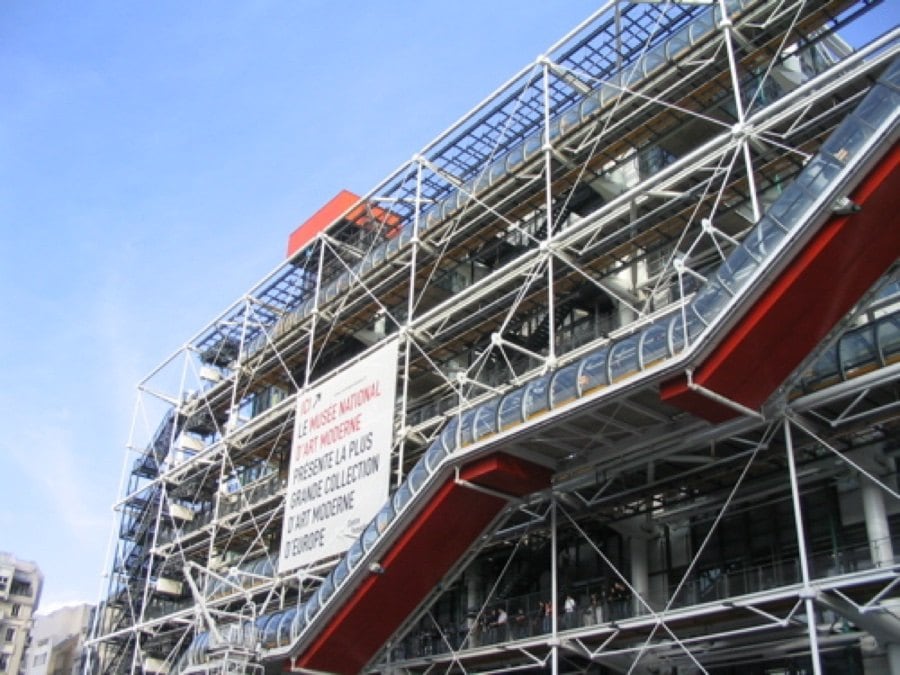 Centre Pompidou'nun çelik borulu cephesi, kırmızı alt yapılı cam yürüyen merdiven tüpü ve afiş
