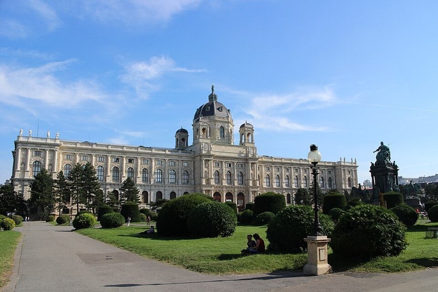 Kubbeli neorönesans Kunsthistorisches Museum binası, önünde budanmış çalılar ve çimenlik, mavi gökyüzü