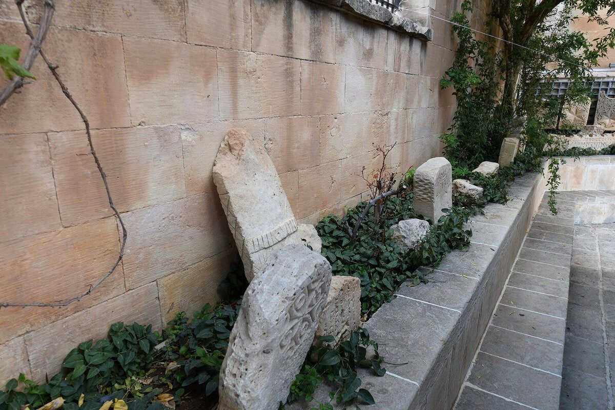 Mardin Müzesi'nin açık teşhir alanında duvar dibine dizilmiş, kabartma bezemeli taş mezar ve mimari parçaları