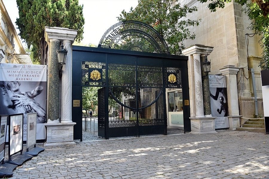 İstanbul Arkeoloji Müzeleri'nin sütunlu taş girişi ve siyah ferforje kapısı, önünde parke taşlı avlu