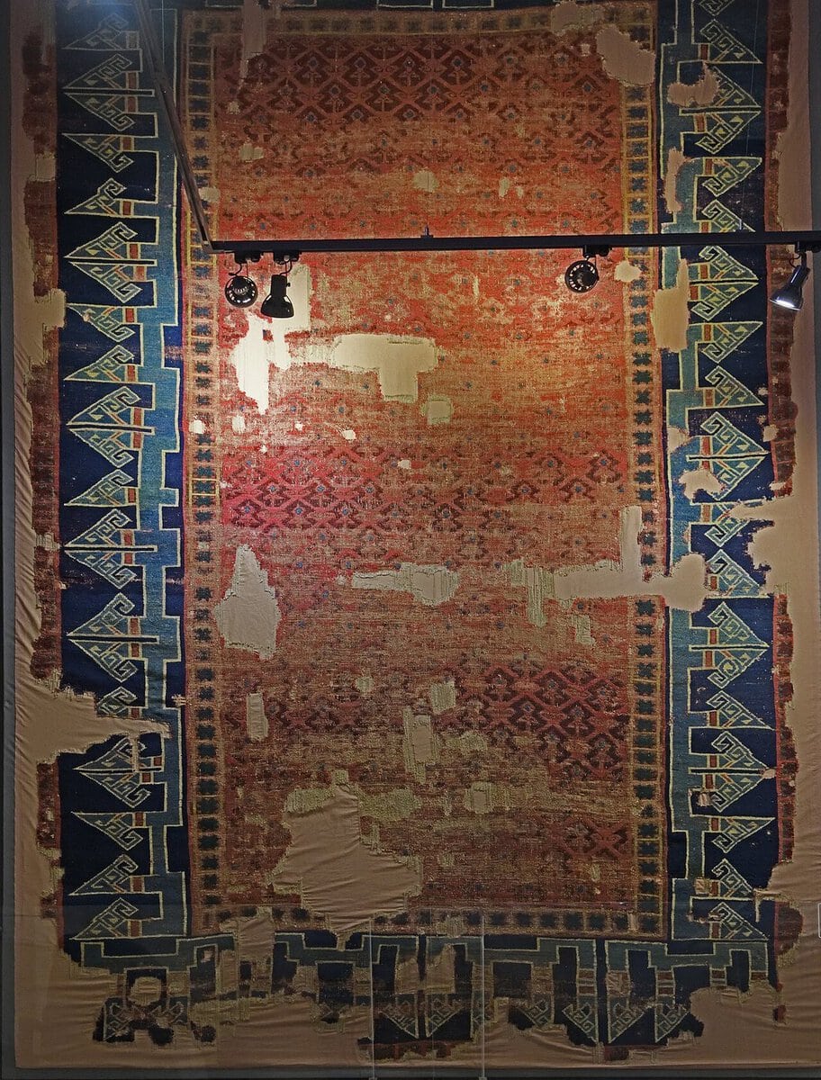 Kufi yazı benzeri mavi bordürlü, kırmızı zeminli 13. yüzyıl Selçuklu halısı